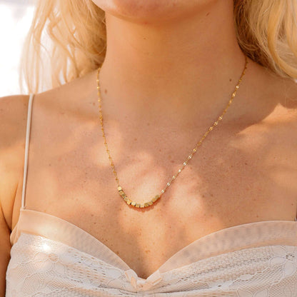 Close-up of a person wearing a gold necklace with a blurred background