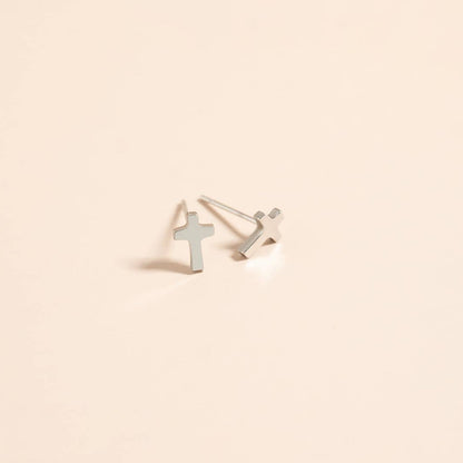 Silver cross-shaped earrings on a beige background