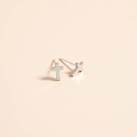 Silver cross-shaped earrings on a beige background