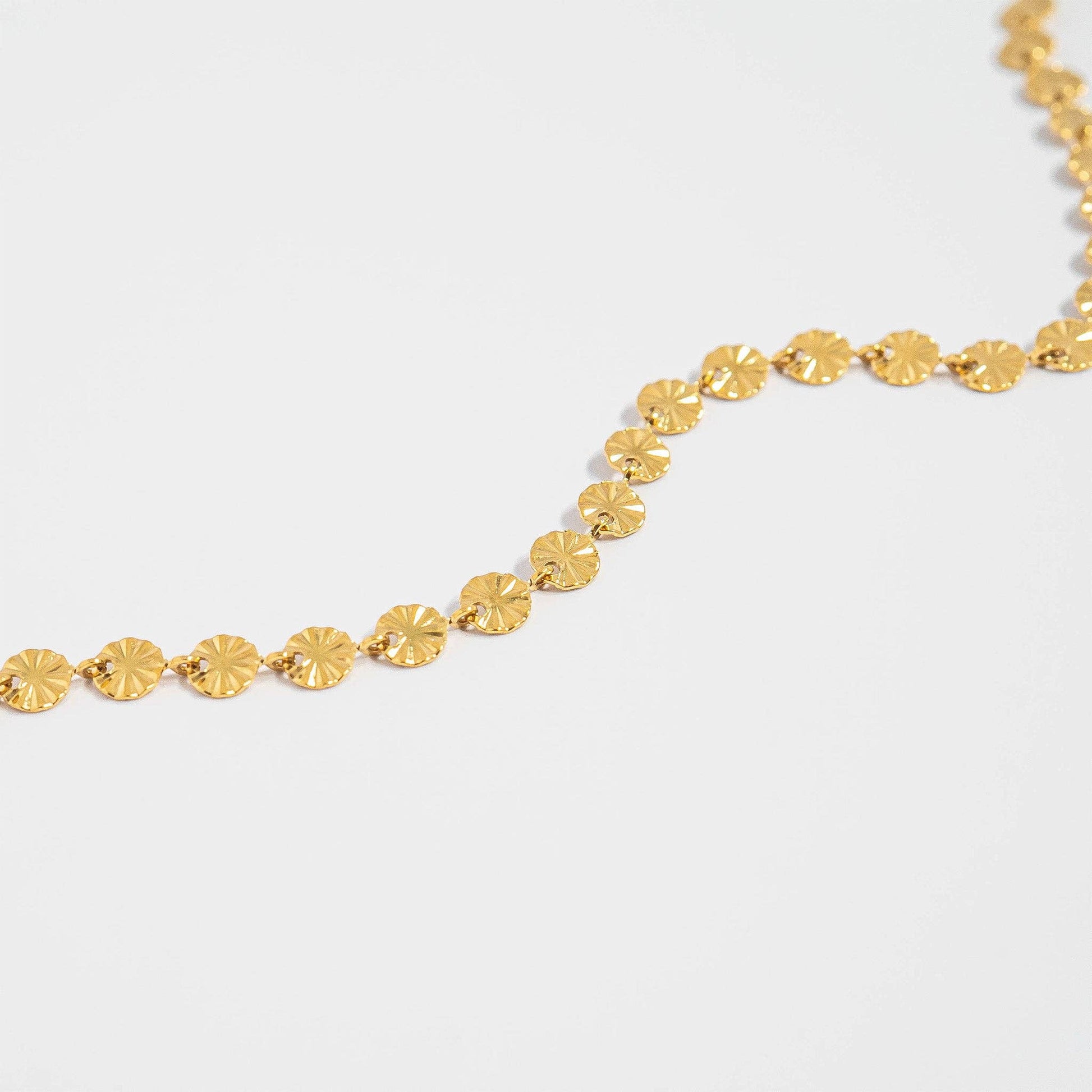 Gold necklace on a light gray background