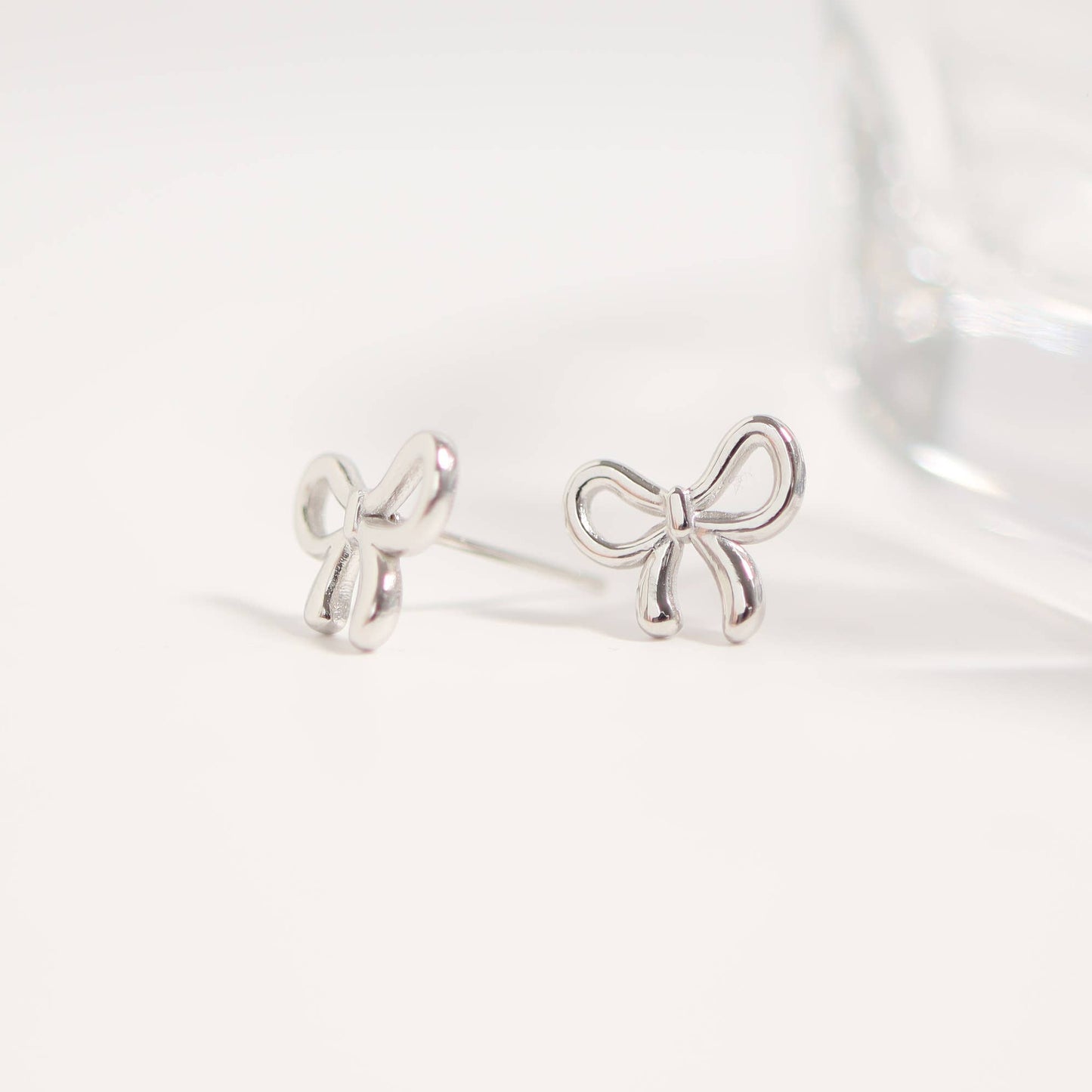 Silver bow-shaped earrings on a white background