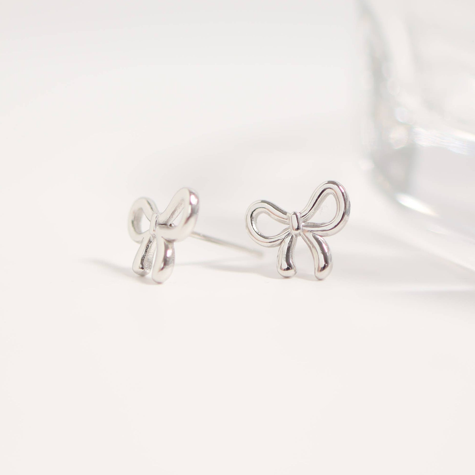Silver bow-shaped earrings on a white background